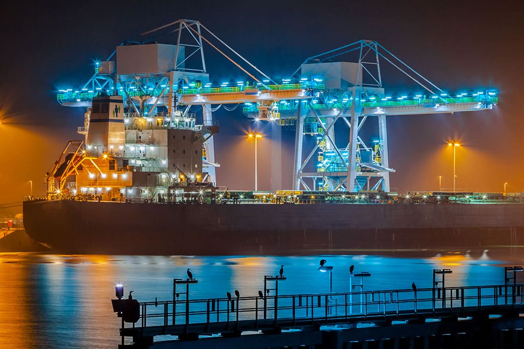 A ship picking up cargo at night at Jebel Ali port - Al Talib Shipping Company Dubai